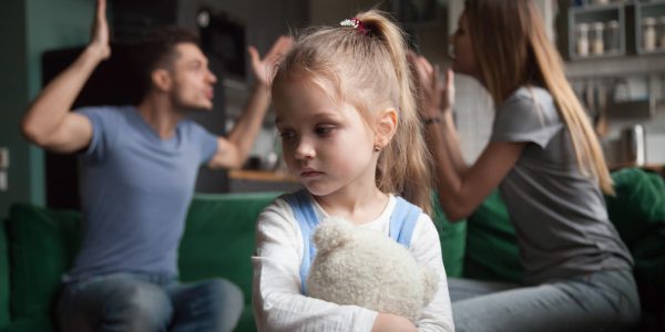 Kid daughter feeling upset while parents fighting at background Child & parents arguing in the background